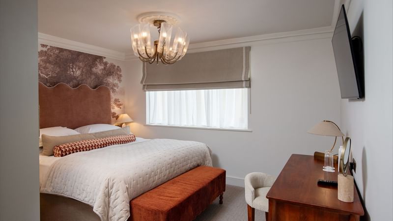 Elegant bedroom with large bed, chandelier, and modern furniture at The Capital Hotel, Apartments & Townhouse - London.
