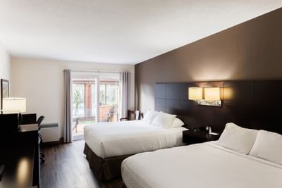 Two beds with wall lamps, and a glass sliding patio door in Royalty Two Queen with Patio at Rodd Royalty