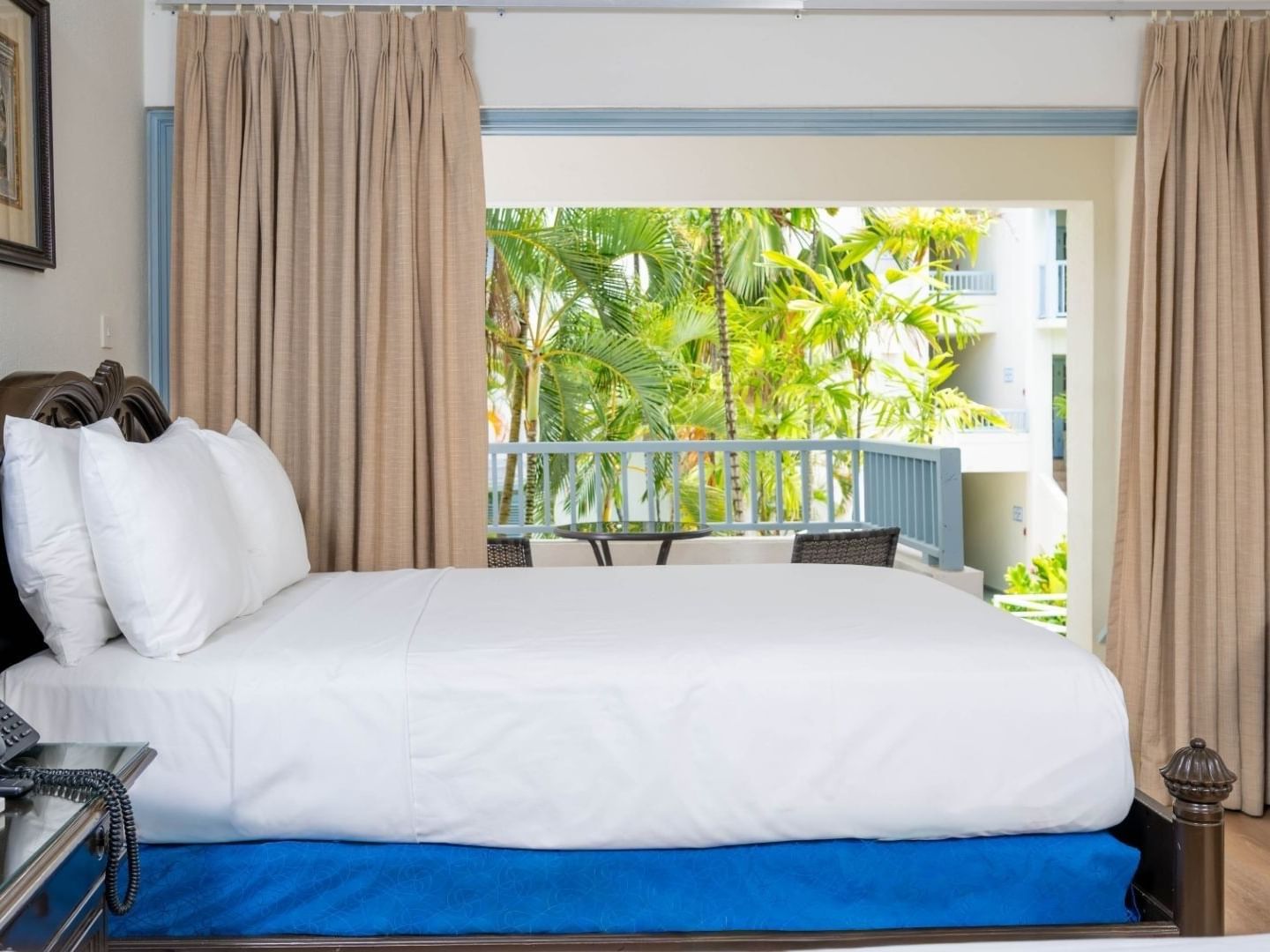 A comfortable hotel room with a bed, balcony, and tropical view at Savannah Beach Hotel.