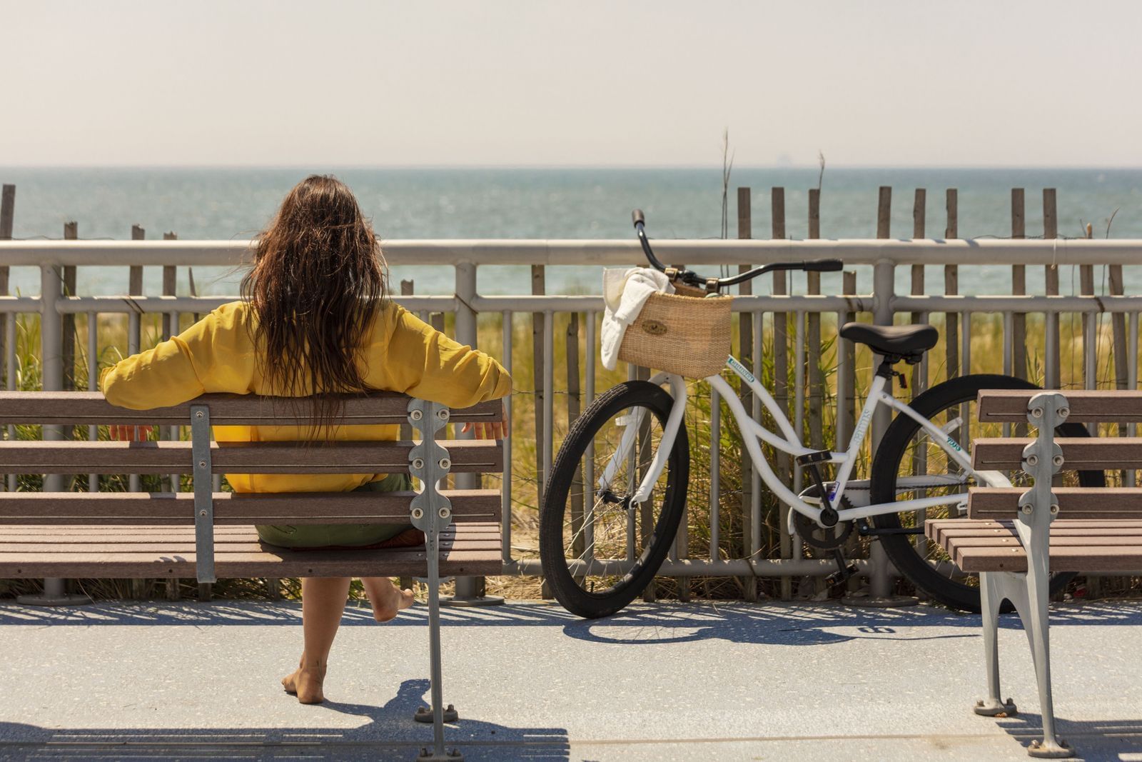 Lady sitting on a bench by the beach near The Rockaway Hotel