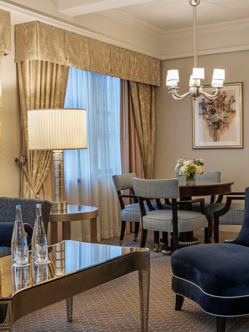 On The Avenue One Bedroom Suite lounge with a velvet blue chair with glass table, and dining corner at Warwick New York