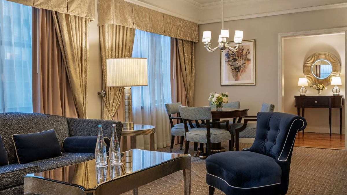 On The Avenue One Bedroom Suite lounge with a velvet blue chair with glass table, and dining corner at Warwick New York