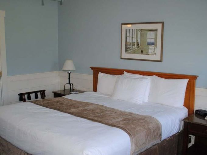 Comfy bed with wall image in Main Lodge Standard Queen room at Sebasco Harbor Resort by Ogunquit Collection