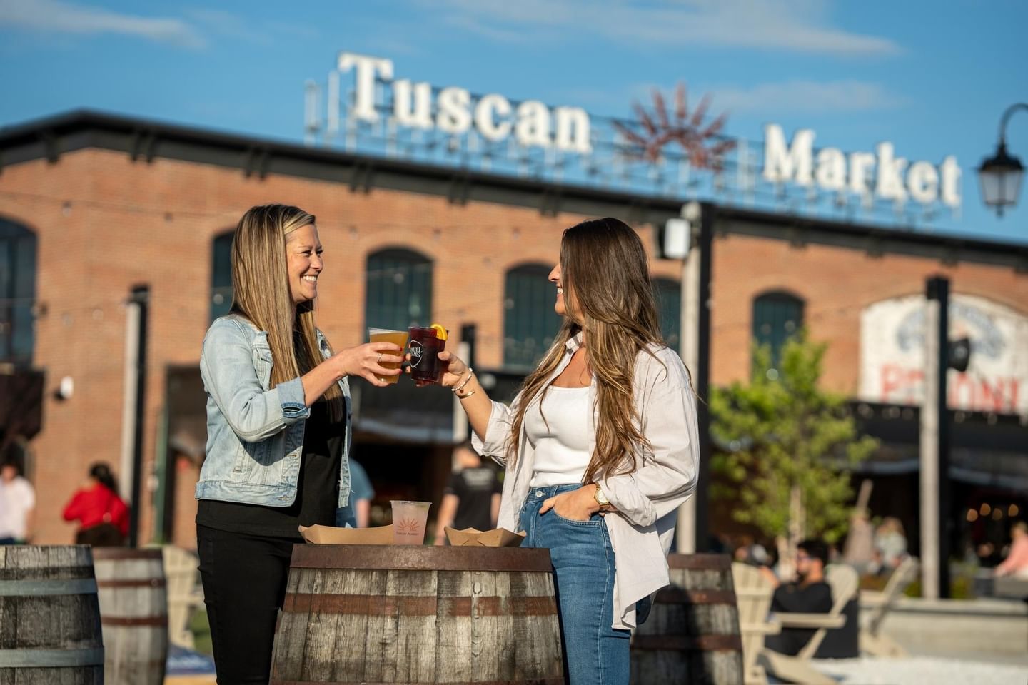Two ladies toasting beer over a barrel near Beer Garden at The Artisan Hotel at Tuscan Village