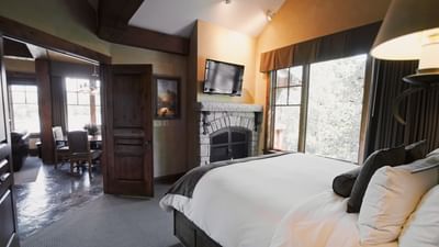 TV and fireplace facing the bed by the window in the living area of Cottage Suites at Hotel Park City Autograph Collection