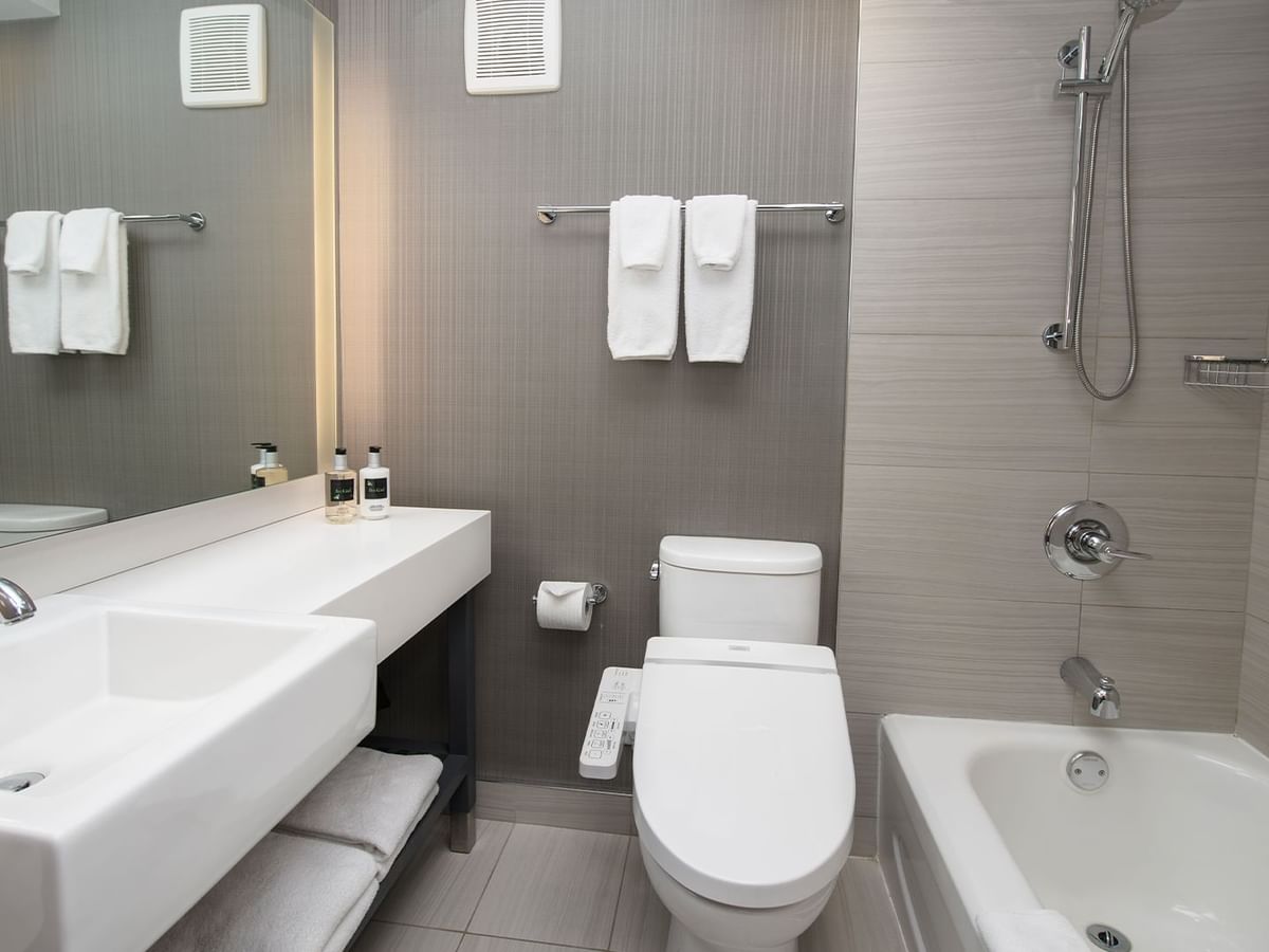 Modern bathroom with white sink, toilet, and bathtub, and white towels.