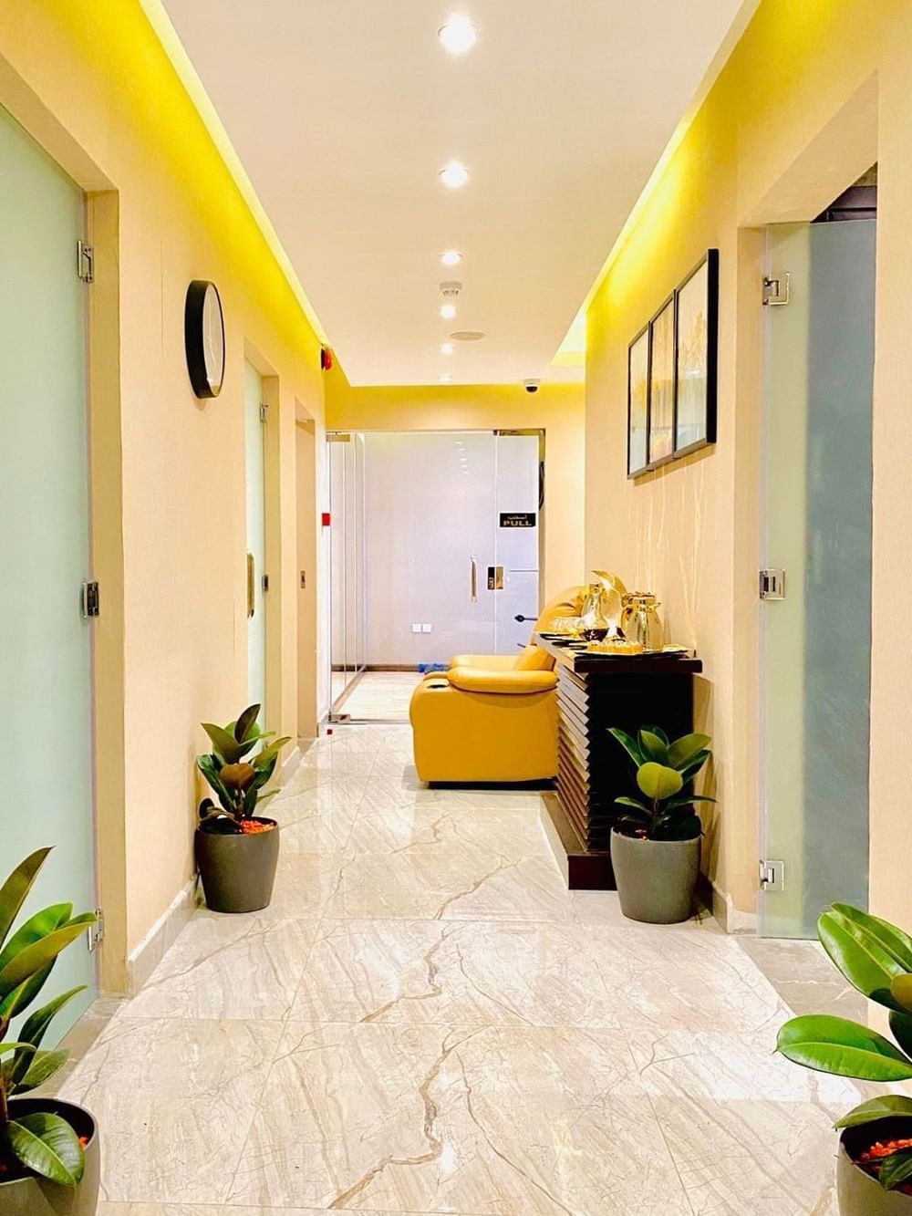 Wellness corridor, featuring a yellow chair near plants by a refreshment console at Naviti By Warwick Dammam