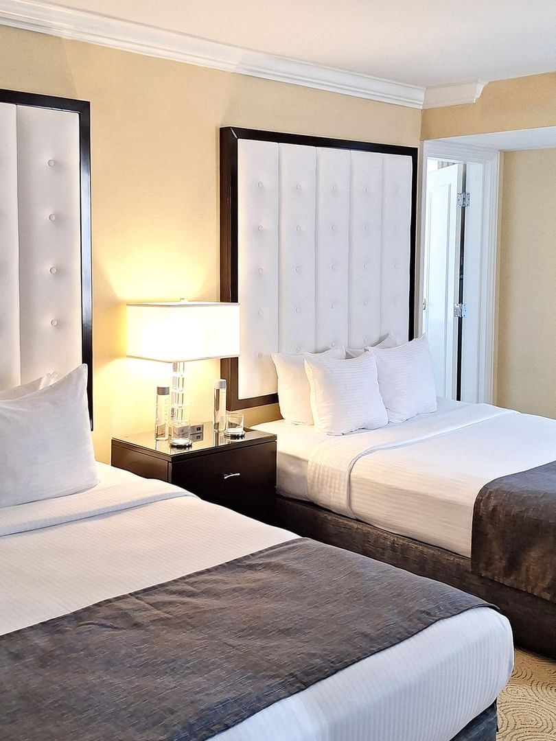 Two queen beds with tufted headboards and bedside lamps in a Premium Suite at Warwick Allerton Chicago
