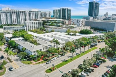 Aerial view of Tradewinds Apartment Hotel nestled among palm trees with the Miami skyline in the background