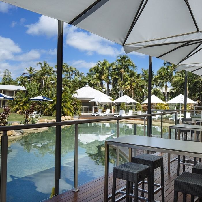 Dining area with modern tables by a pool in Celsius Restaurant & Bar at Mercure Hotel Townsville
