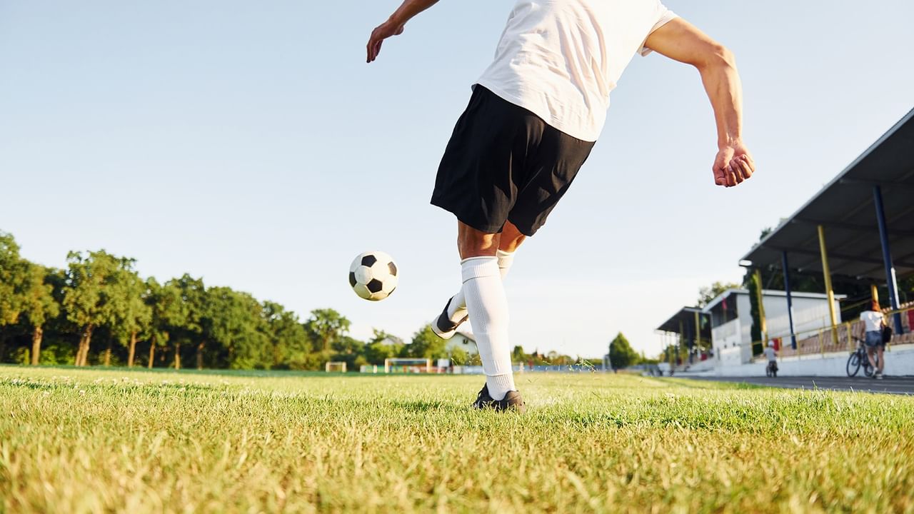 A man kicks a soccer ball on a field.