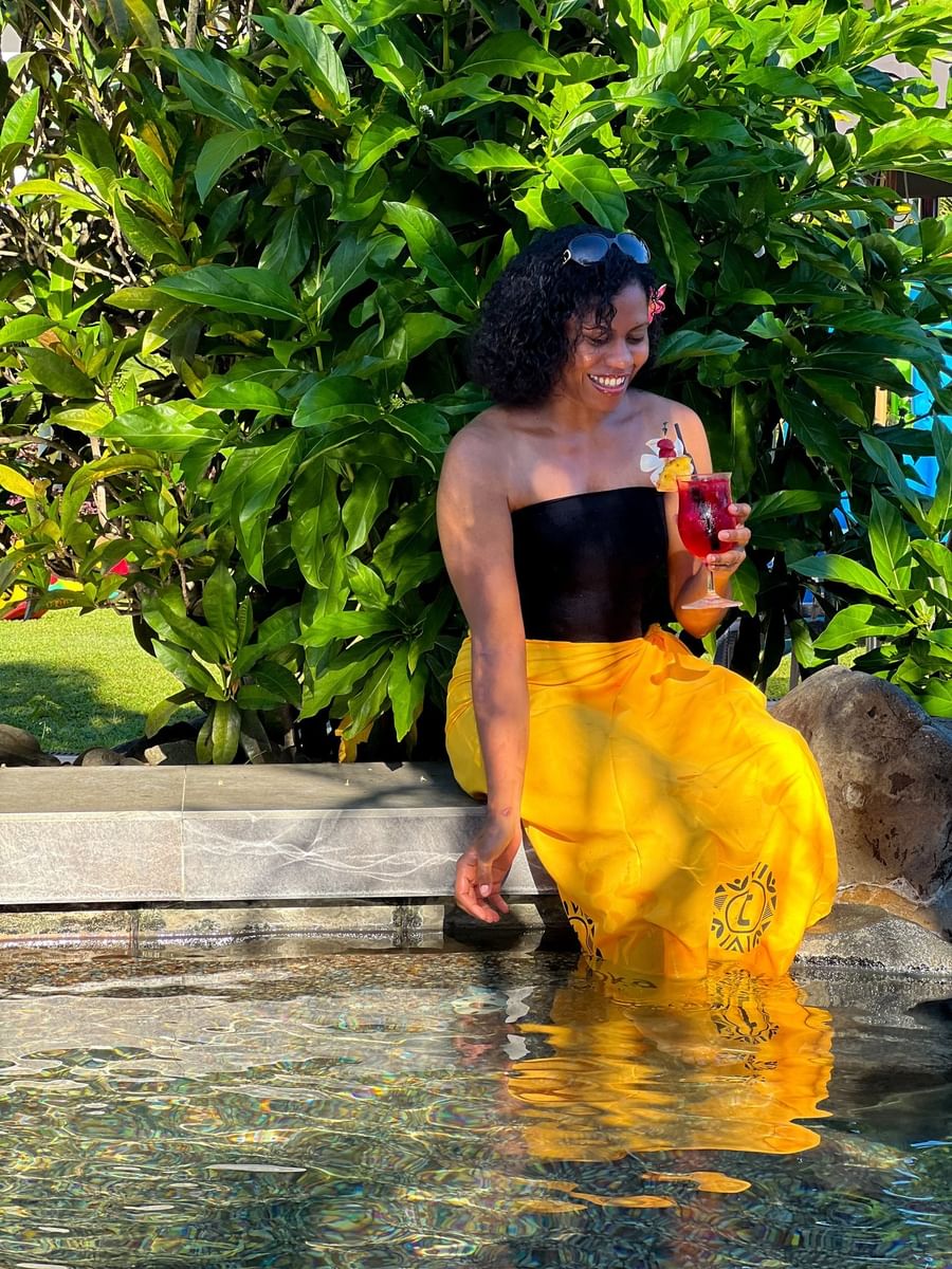 Guest with a drink sitting by a rock pool surrounding tropical plants at TokaToka Resort Nadi Fiji