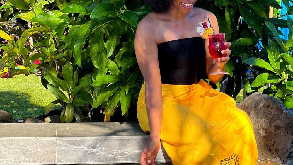 Smiling woman with tropical drink by the pool at Tokatoka Resort in Nadi, Fiji.