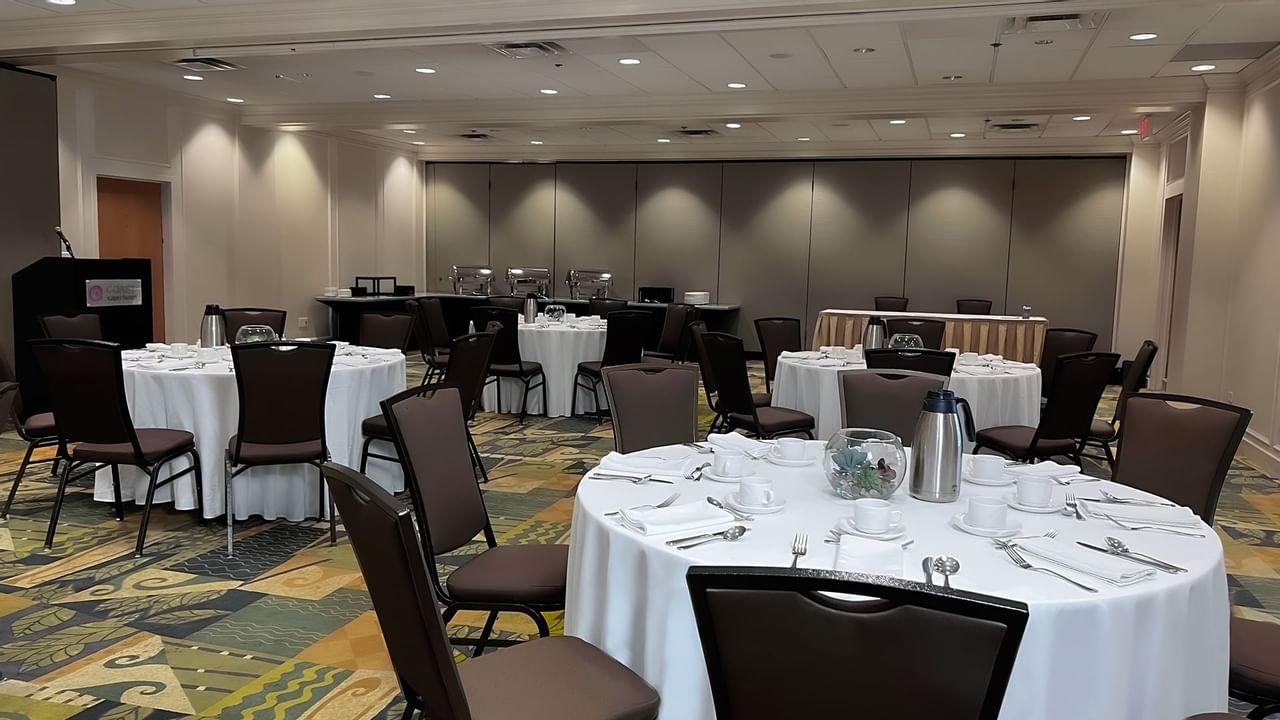 Ballroom with round tables and chairs facing podium