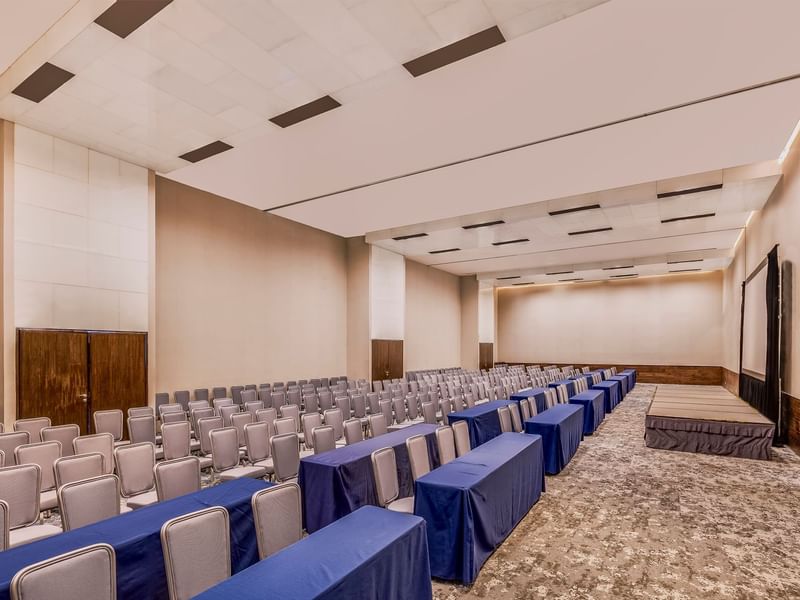 A large conference room with rows of chairs and tables covered in blue cloth at Live Aqua Monterrey.