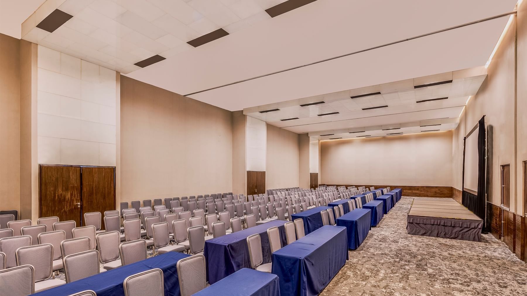 A large conference room with rows of chairs and tables covered in blue cloth at Live Aqua Monterrey.