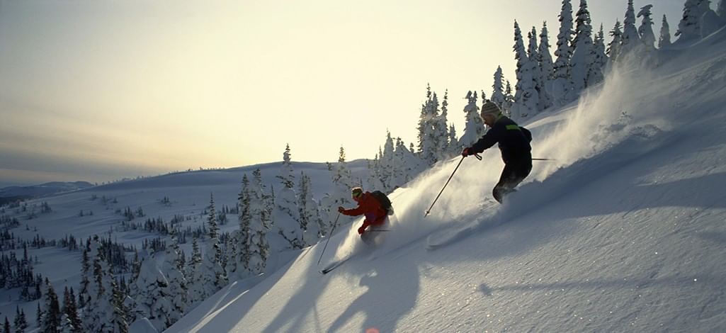 Two skiers head down a ski hill near Canmore.