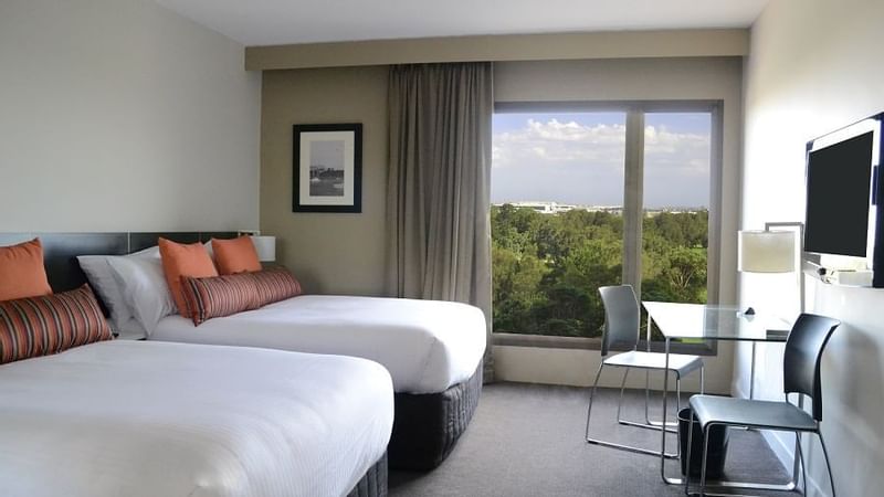 Two beds with a work desk by the window with scenic view in the Superior Room at Novotel Sydney International Airport