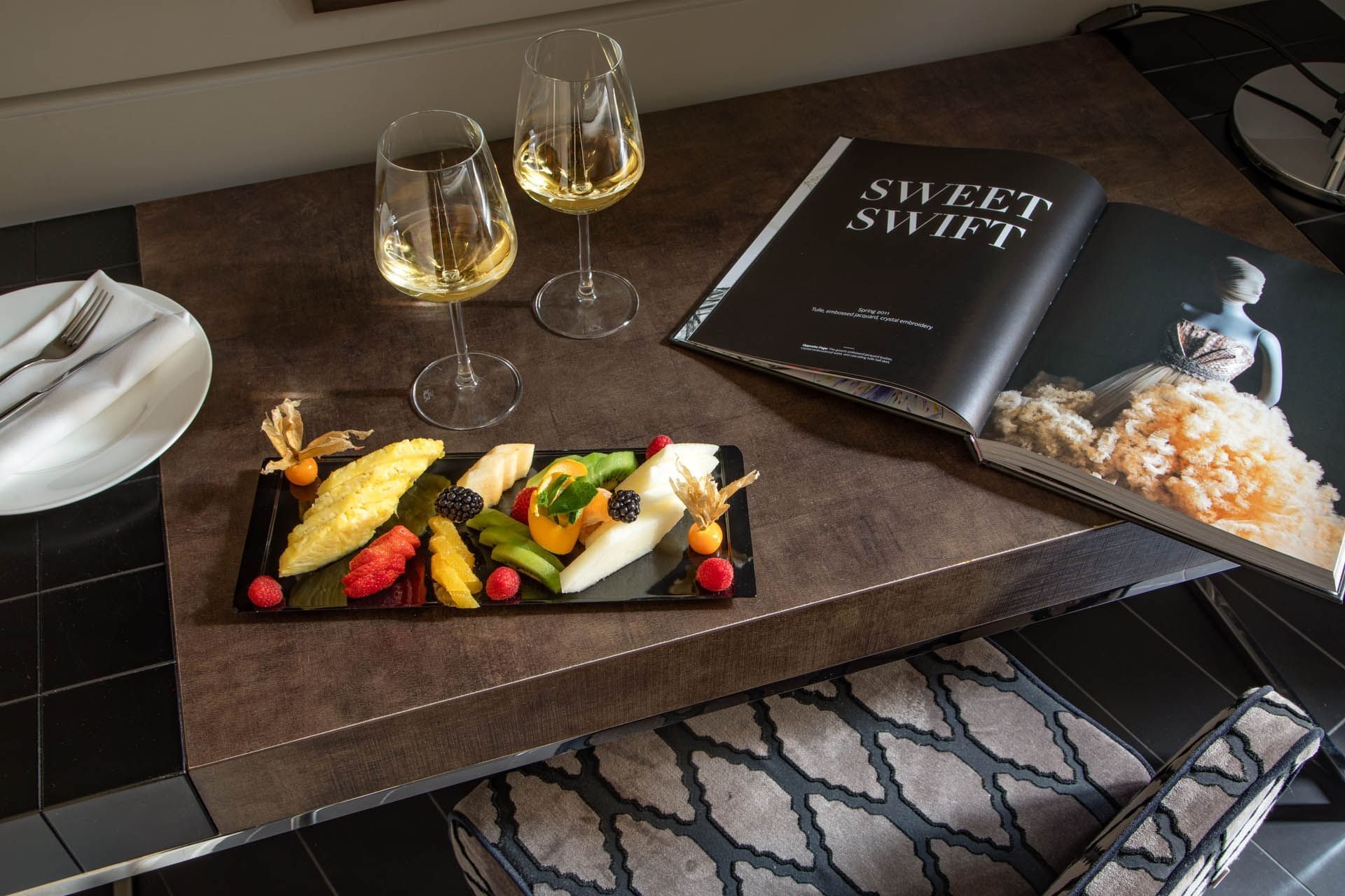 White wine & fruit platter served by a magazine on a table in Superior Room at The Style