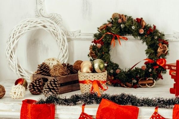 A white table decorated with wreaths, pinecones, and seasonal Christmas decor.