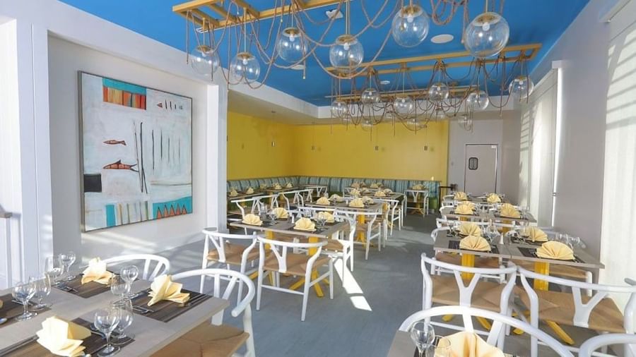 Tables by white chairs under globe lights in Tings on a Stick painting at Warwick Paradise Island Bahamas