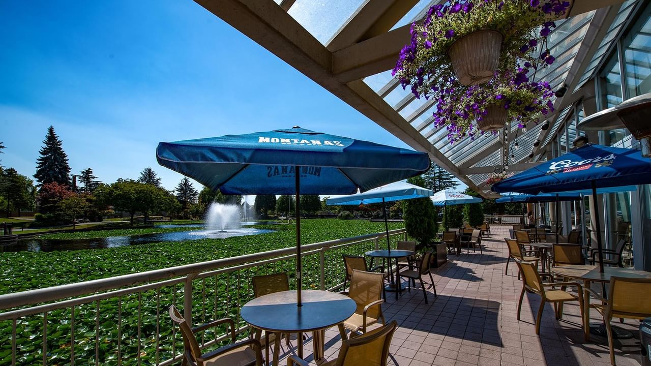 Montana’s BBQ & Bar patio with tables and umbrellas overlooking a landscaped pond with a fountain