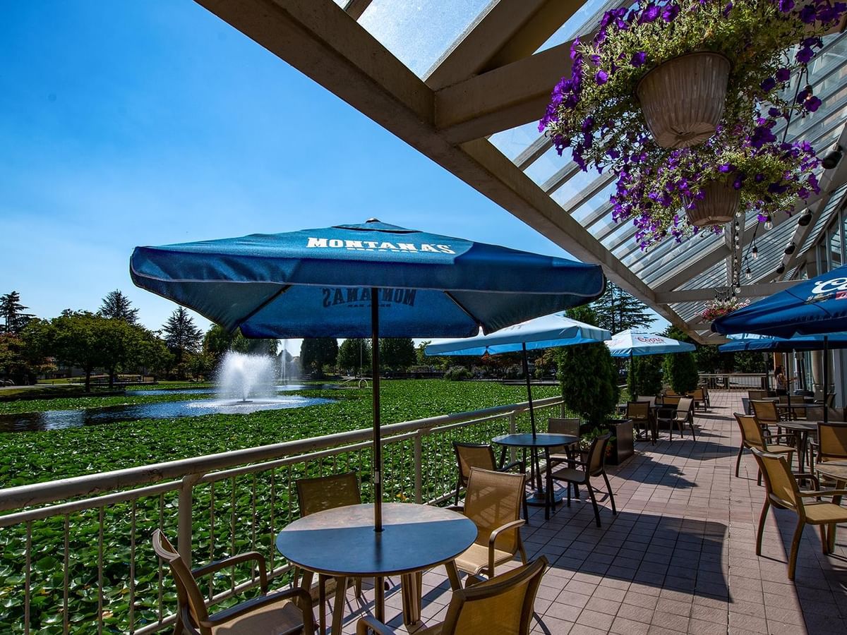 Montana's BBQ & Bar restaurant patio with tables and umbrellas overlooking a landscaped pond