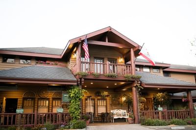 Wooden building with American and Californian flags, balcony, plants, and registration signs.
