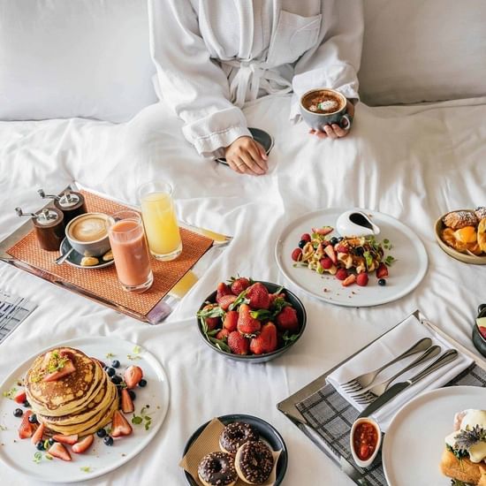 Lady enjoying breakfast on bed at Pullman Sydney Olympic park 