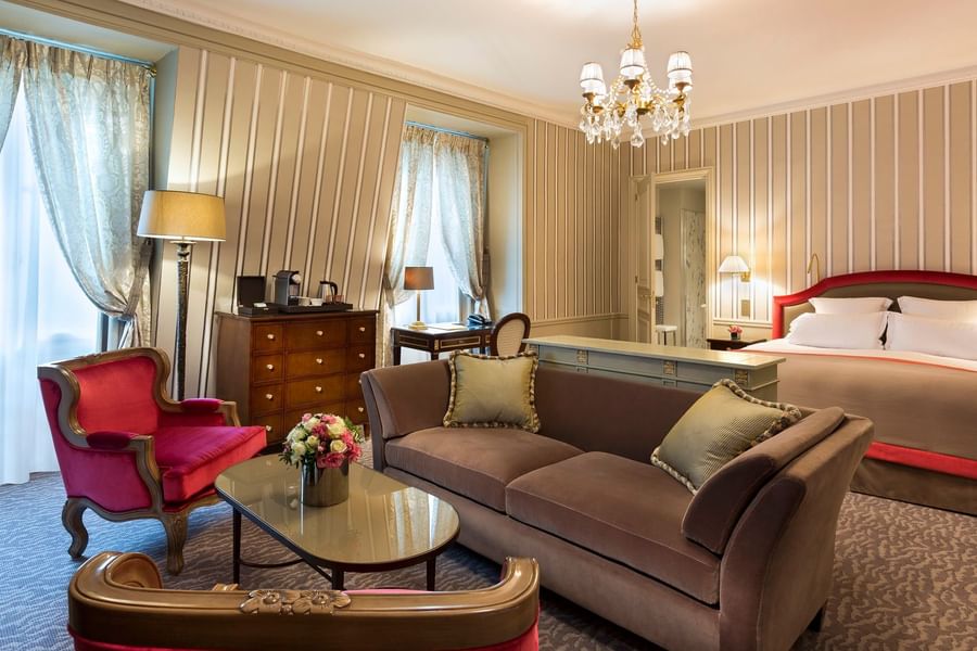 Living area with a plush sofa near bed in Deluxe Suite Parisienne at Hotel Westminster Paris