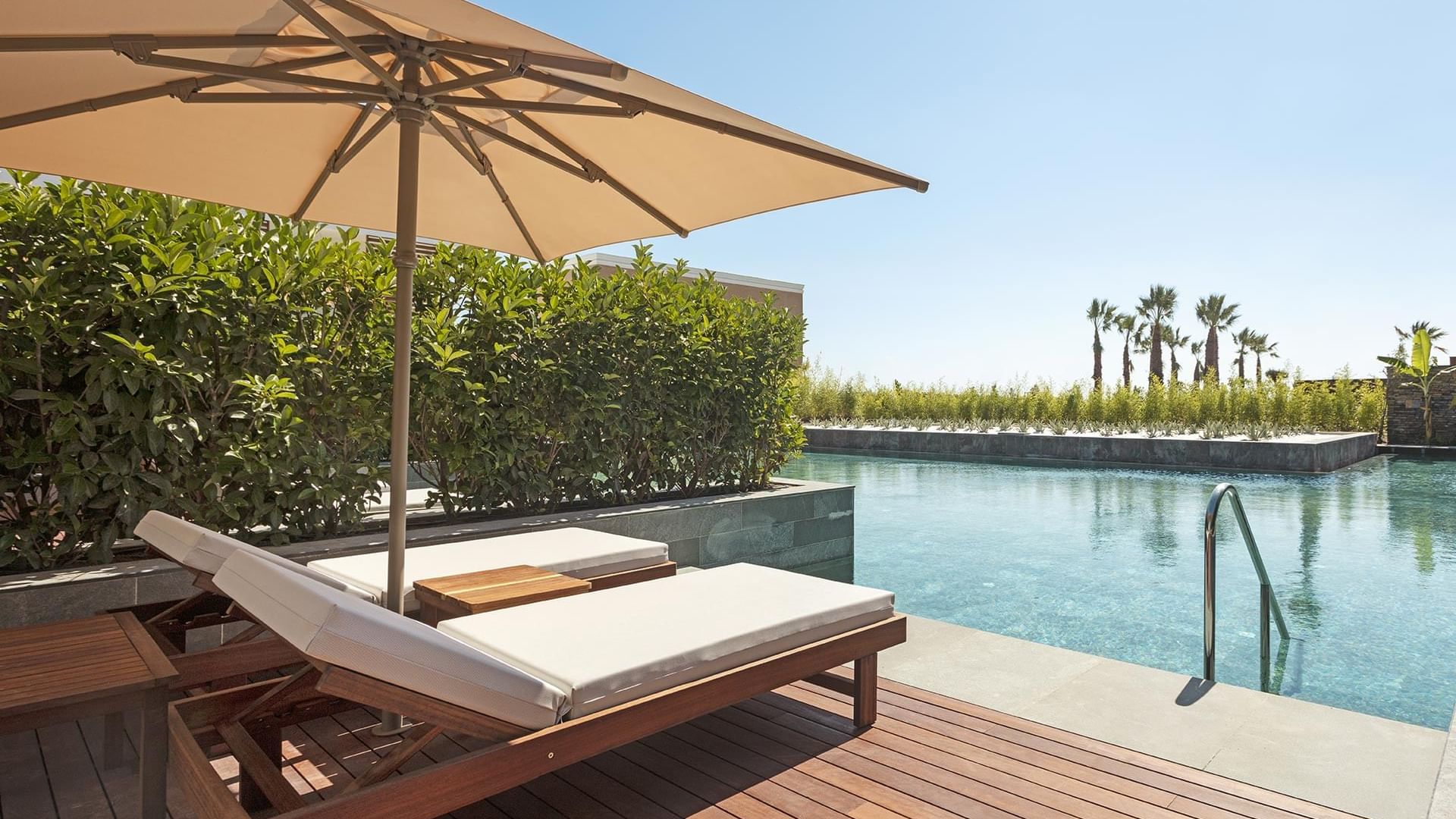 Poolside loungers with patio umbrella at Lagoon Beach Swim-up Room in Cullinan Belek