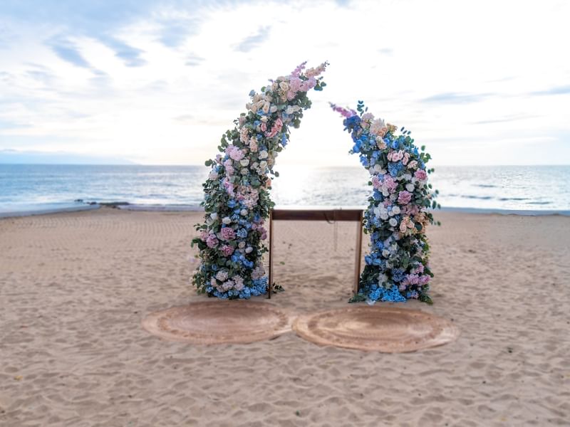 Floral arches and ceremony setup on sandy beach at Fiesta Americana Riviera Nayarit Resort & Spa.