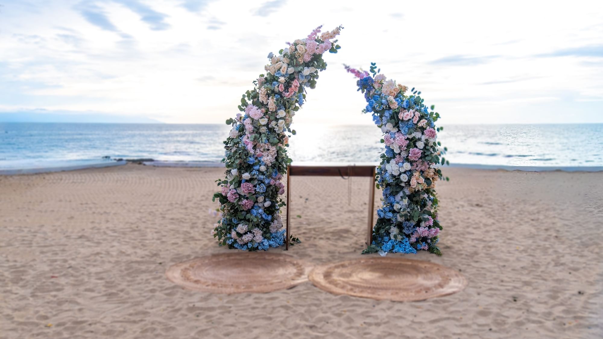 Floral arches and ceremony setup on sandy beach at Fiesta Americana Riviera Nayarit Resort & Spa.