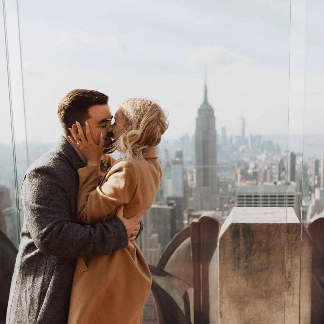 A couple kissing in front of a city view with the Empire State Building