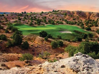 Lush Towa Golf Club course near Hilton Santa Fe Buffalo Thunder, nestled in a desert landscape under a vibrant sky