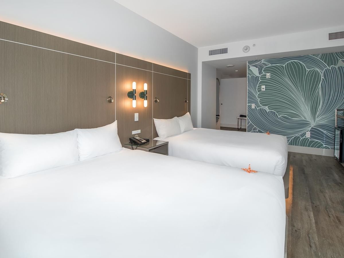 Two queen beds with white linens in a spacious room.