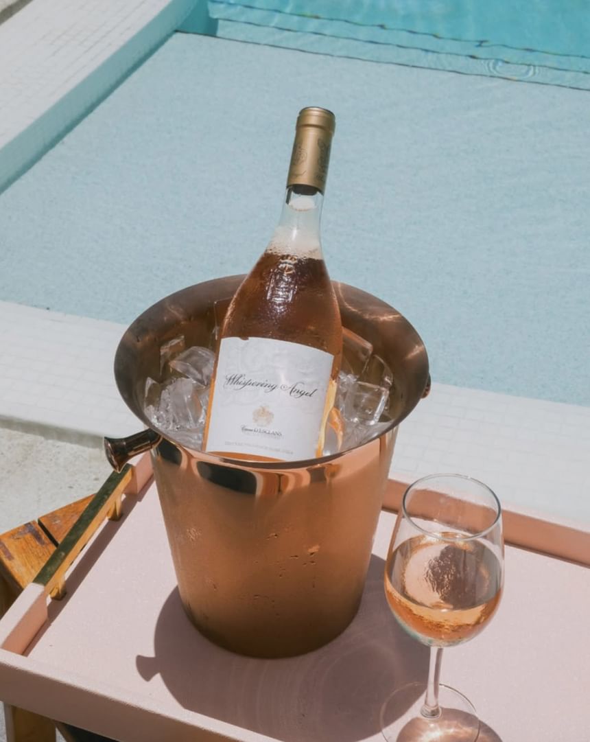 Bottle of chilled rosé wine in a copper ice bucket next to a glass of wine by the pool at The Plymouth Hotel South Beach