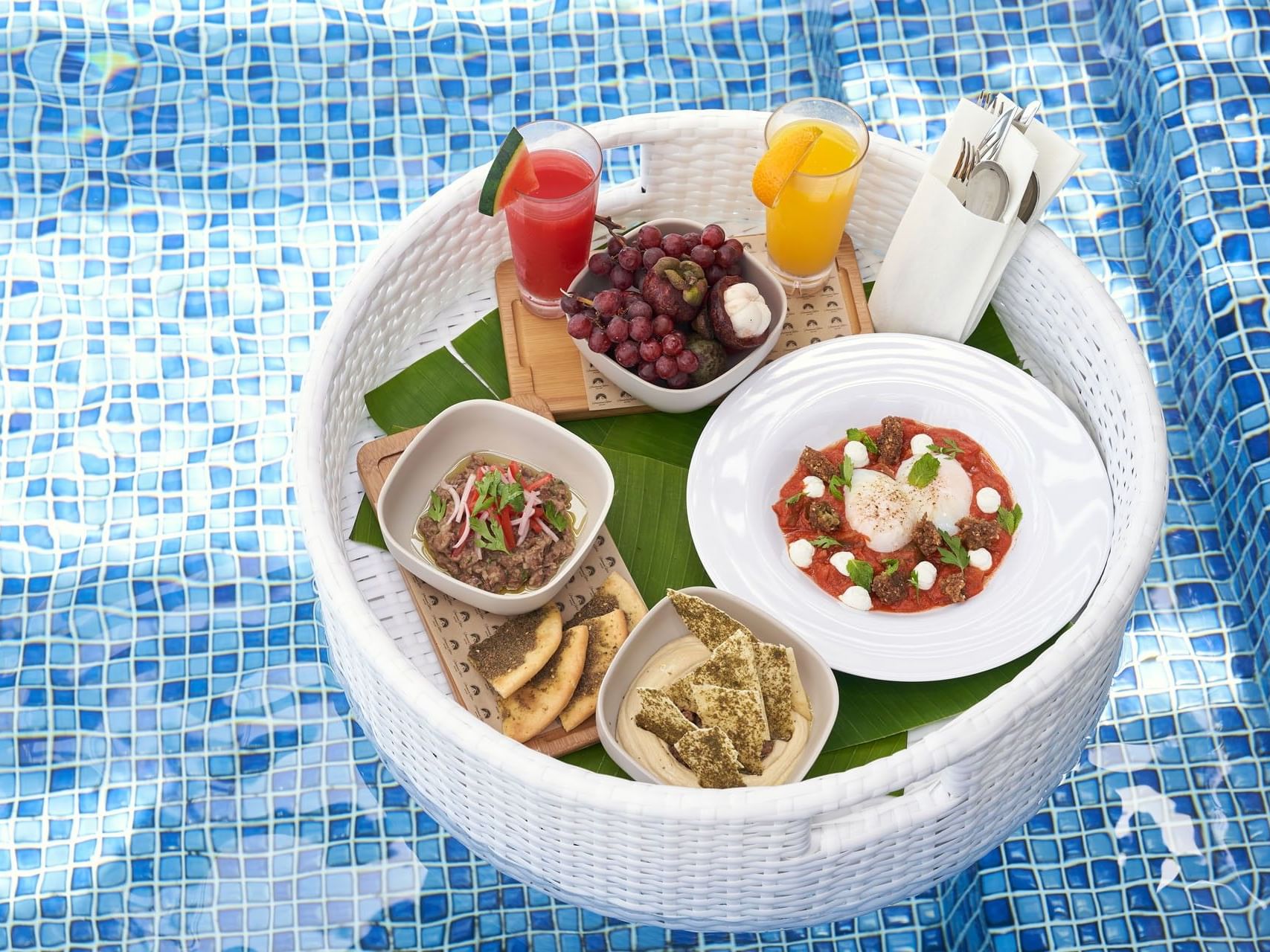 Floating Breakfast tray holding fresh fruit juices, flatbread, and a poached egg dish in the pool at Malibu Sky Lounge & Bar