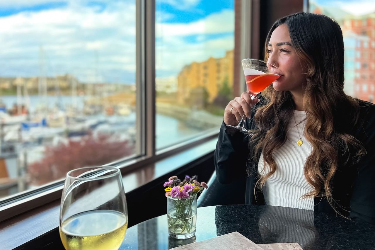 Woman enjoying a cocktail overlooking view of marina