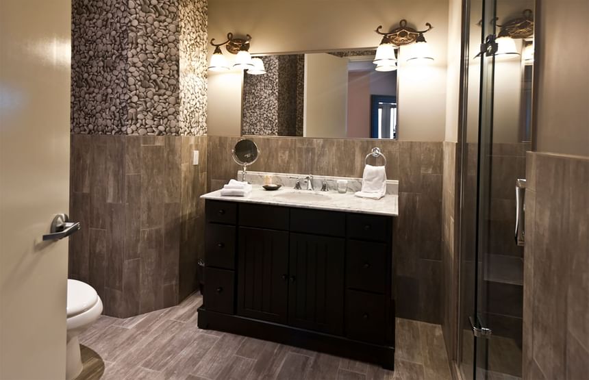 bathroom with stone looking glass walk-in shower and grey counte