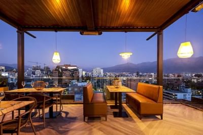 Terrace dining and lounge area overlooking the city and mountains in the evening at Hotel Nodo