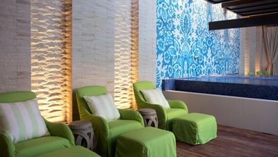 Relaxing spa with green lounge chairs by the pool and a blue-tiled wall in The Residences at Seafire