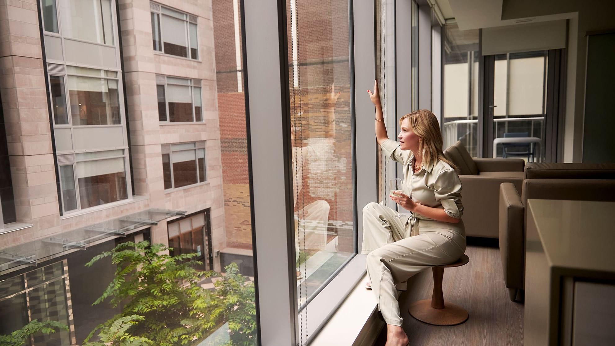 A woman holding a glass of wine by a window at ReStays Ottawa