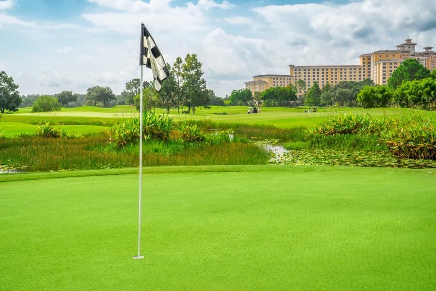 A black and white checkered flag at a golf course hole with a grand hotel in the background.