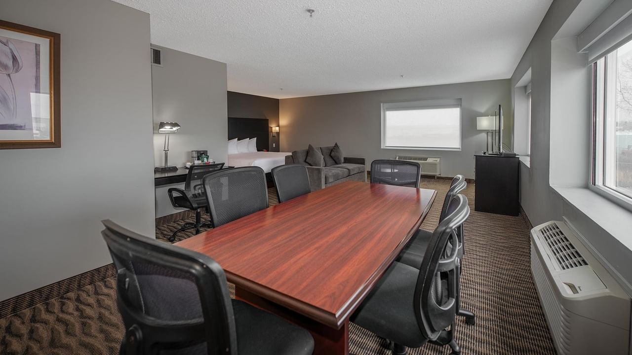 Modern hotel suite with a large table, couch, and bed.