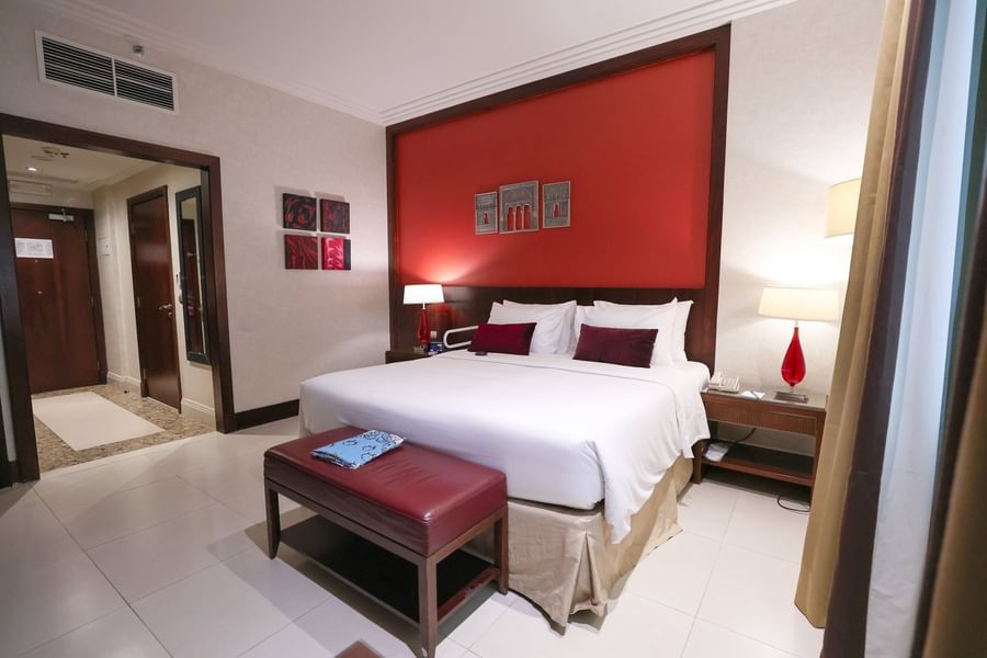 Accessible room featuring a red accent wall with king bed and plush furniture at Saja by Warwick Makkah
