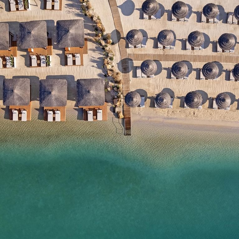 Идиллический пляж с шезлонгами и зонтиками в Titanic Luxury Collection Bodrum.