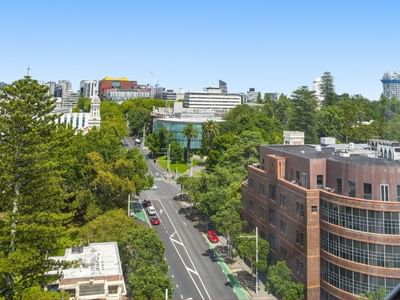Elevated view of city with buildings and trees from a window at Student Living Auckland – Anzac.
