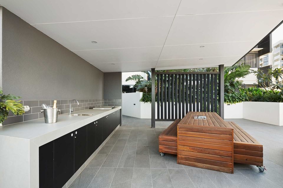 Outdoor BBQ area with arranged wooden seats and vanity with tiled floors at Alcyone Hotel Residences