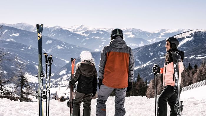 Three skiers standing with skis in snowy mountains near Falkensteiner Hotel Sonnenalpe